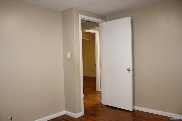 unfurnished room with dark wood-type flooring and baseboards