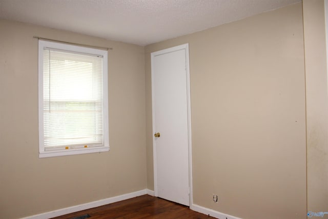 unfurnished room with dark wood finished floors and baseboards
