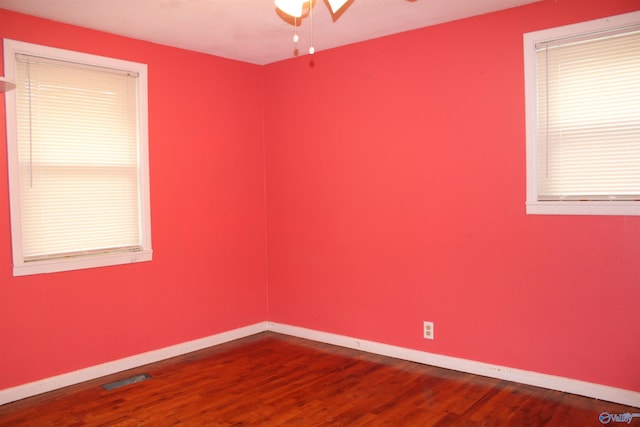unfurnished room with visible vents, a ceiling fan, baseboards, and dark wood-style flooring