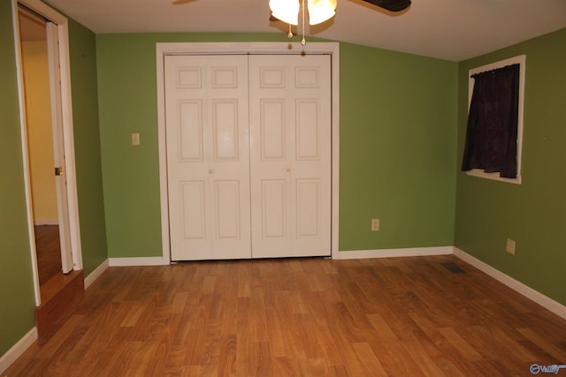 unfurnished bedroom with baseboards, a ceiling fan, wood finished floors, and a closet