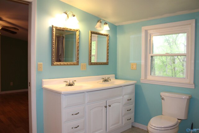 bathroom featuring double vanity, toilet, a ceiling fan, and a sink