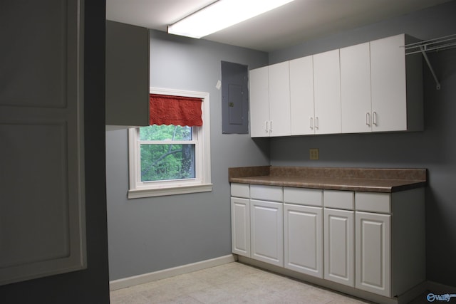 kitchen featuring white cabinets, electric panel, baseboards, and dark countertops