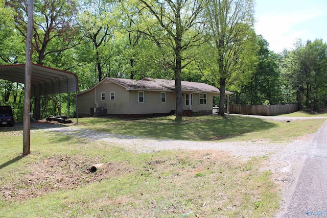 view of front of property with dirt driveway, a detached carport, a front yard, and fence