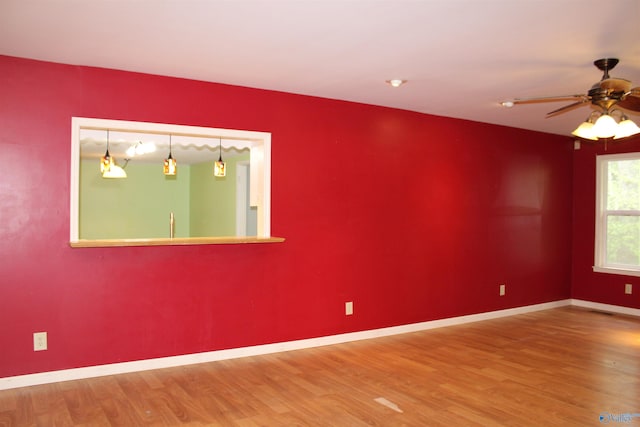 spare room with baseboards, a ceiling fan, wood finished floors, and visible vents