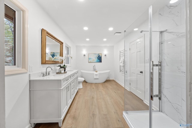 full bath featuring recessed lighting, a freestanding tub, vanity, and a marble finish shower