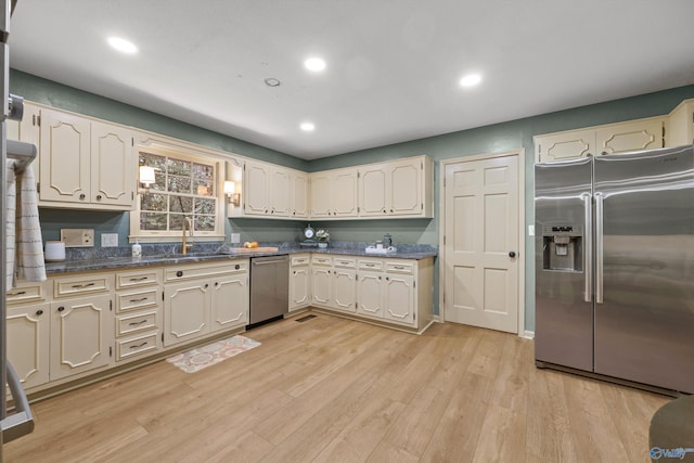 kitchen featuring cream cabinetry, sink, light hardwood / wood-style flooring, and stainless steel appliances