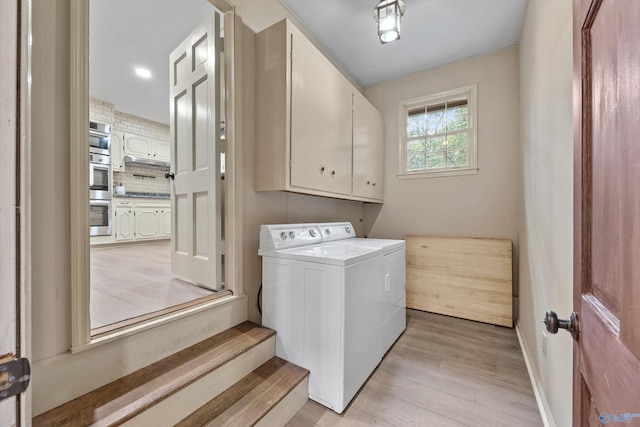 laundry area with washer and clothes dryer, light hardwood / wood-style flooring, and cabinets