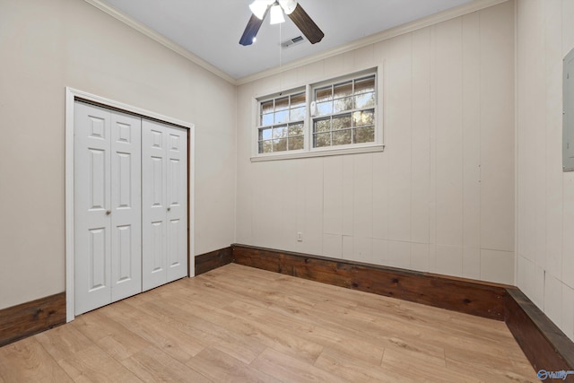 unfurnished bedroom featuring crown molding, light hardwood / wood-style floors, ceiling fan, and a closet