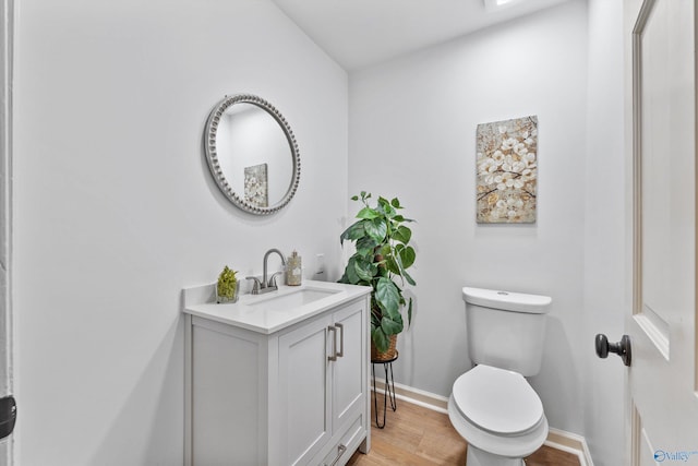 bathroom with wood finished floors, baseboards, vanity, and toilet
