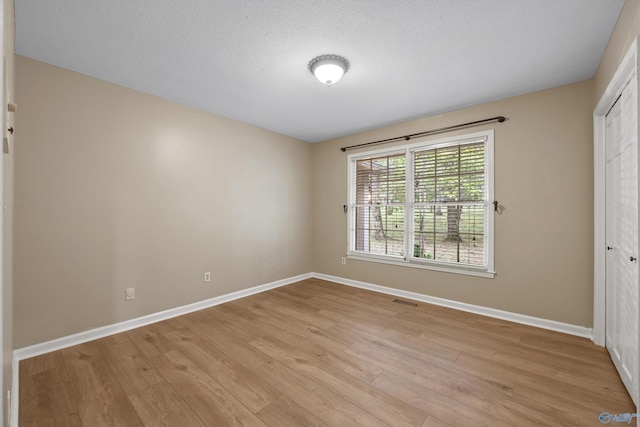 unfurnished bedroom with light wood-style floors, a closet, baseboards, and visible vents