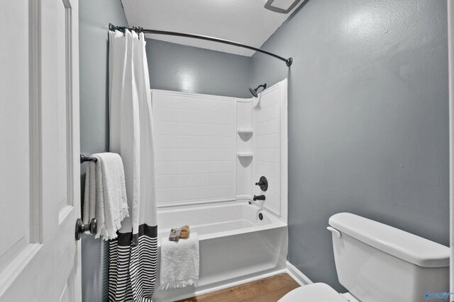 bathroom with shower / bath combination with curtain, baseboards, wood finished floors, and toilet