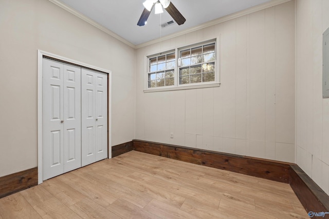 unfurnished bedroom featuring a ceiling fan, a closet, light wood-style floors, ornamental molding, and visible vents