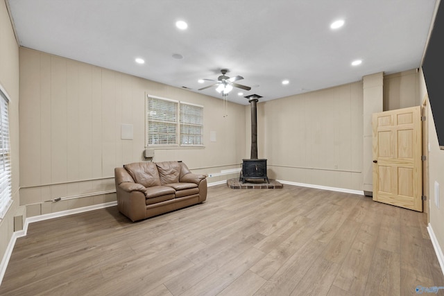 sitting room featuring ceiling fan, a wood stove, light wood finished floors, and recessed lighting