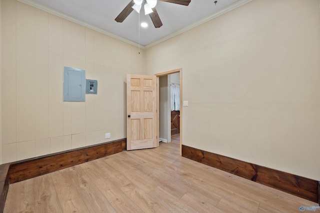 spare room featuring electric panel, baseboards, a ceiling fan, wood finished floors, and ornamental molding