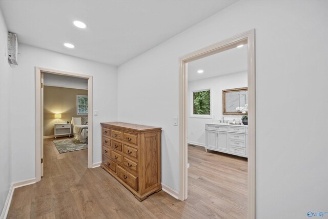 hall with baseboards, recessed lighting, a sink, and light wood-type flooring