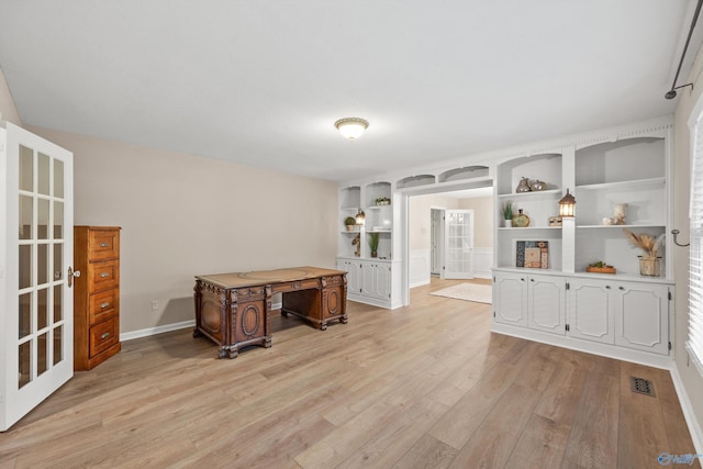unfurnished office with light wood finished floors, french doors, baseboards, visible vents, and built in features