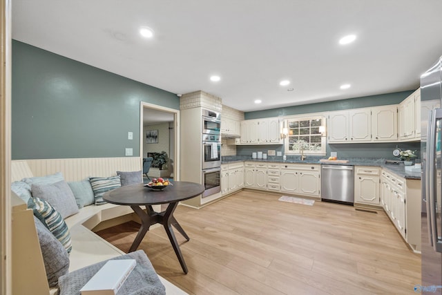 kitchen featuring white cabinets, backsplash, stainless steel appliances, and light wood-type flooring