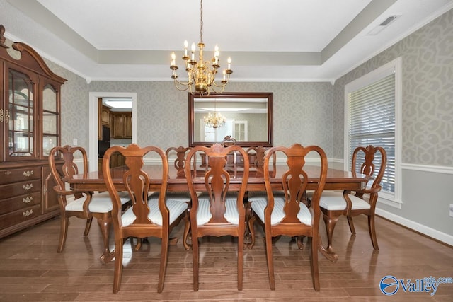 dining space featuring hardwood / wood-style flooring, a tray ceiling, and a chandelier