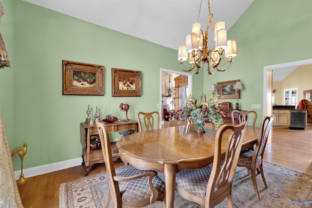 dining area with hardwood / wood-style floors, vaulted ceiling, and a chandelier