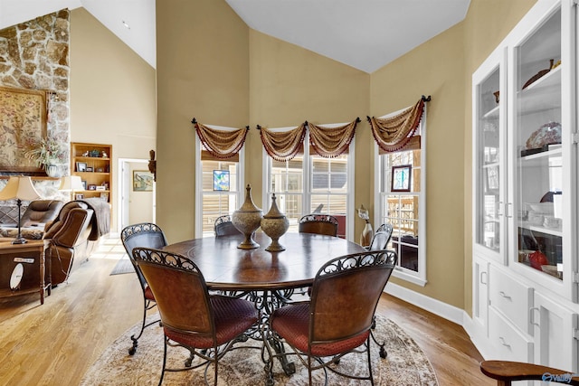 dining space with light hardwood / wood-style flooring and high vaulted ceiling