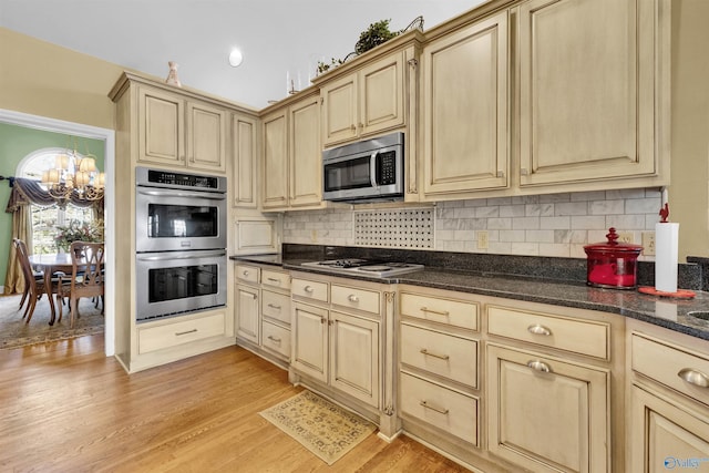 kitchen with dark stone counters, light hardwood / wood-style floors, stainless steel appliances, light brown cabinetry, and decorative backsplash