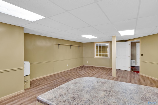 empty room with a drop ceiling and hardwood / wood-style floors