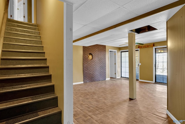 stairs featuring a paneled ceiling, hardwood / wood-style flooring, and wood walls