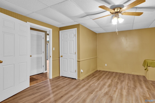 interior space with a paneled ceiling, ceiling fan, and light hardwood / wood-style flooring