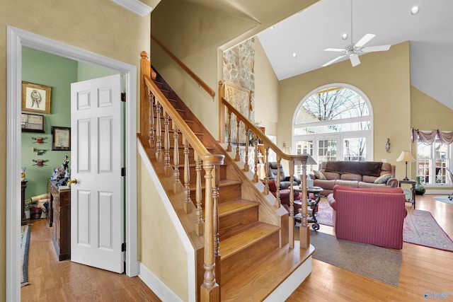 staircase featuring high vaulted ceiling, hardwood / wood-style floors, and ceiling fan