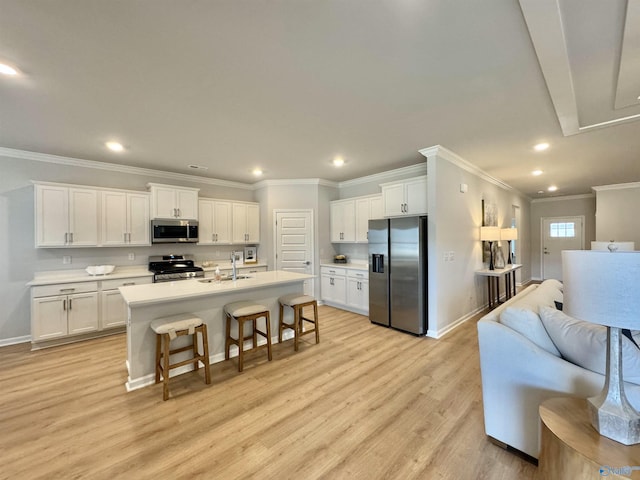 kitchen featuring appliances with stainless steel finishes, a sink, open floor plan, baseboards, and light wood-style floors