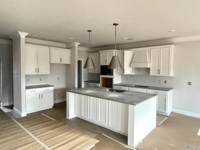 kitchen with custom exhaust hood, a center island, white cabinets, ornamental molding, and stovetop