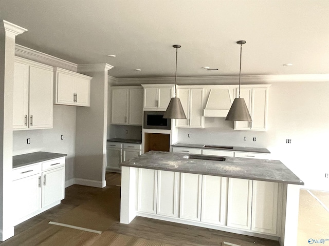 kitchen with pendant lighting, a center island, white cabinets, dark hardwood / wood-style floors, and ornamental molding