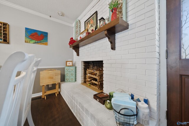 bedroom featuring a textured ceiling, ornamental molding, a brick fireplace, and wood finished floors