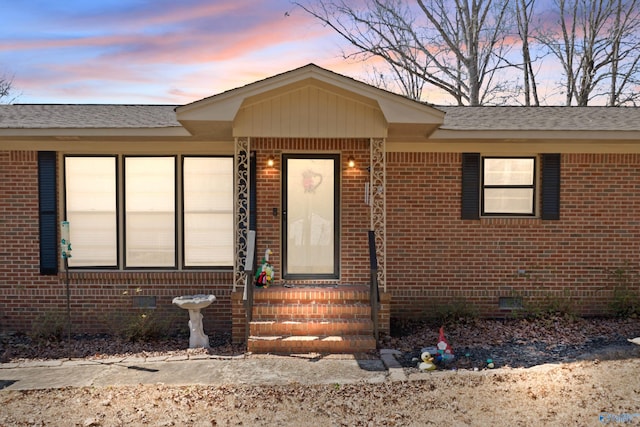 view of front facade with crawl space, brick siding, and roof with shingles