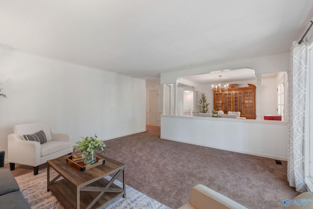 carpeted living area featuring decorative columns, baseboards, and an inviting chandelier