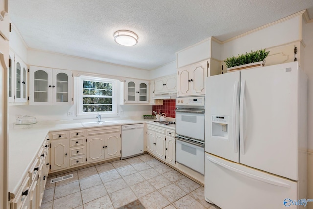 kitchen featuring white appliances, a textured ceiling, backsplash, visible vents, and a sink