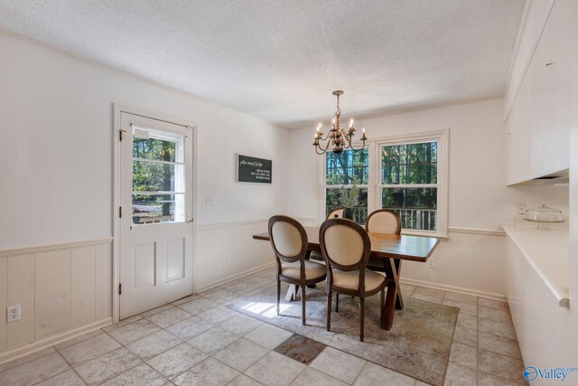 dining room featuring a textured ceiling, an inviting chandelier, and wainscoting