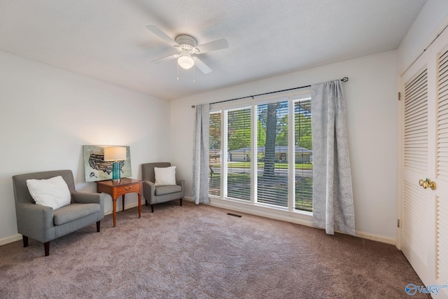 living area with visible vents, baseboards, a ceiling fan, and carpet floors