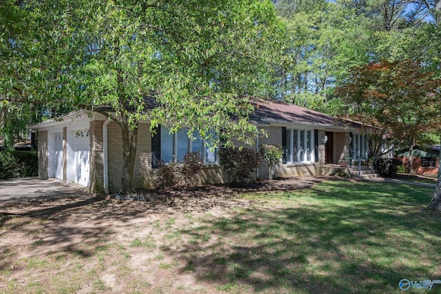 view of front of house featuring a front yard, an attached garage, brick siding, and concrete driveway