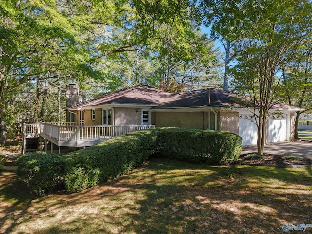 ranch-style house with a front yard, a garage, a chimney, brick siding, and a wooden deck