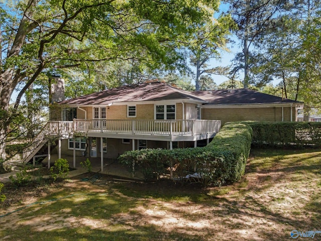 rear view of house featuring brick siding, a chimney, a deck, and stairs