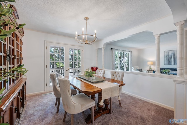 dining space with an inviting chandelier, ornate columns, a textured ceiling, carpet floors, and french doors