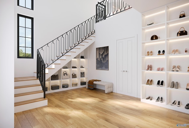 staircase featuring a high ceiling, built in features, and wood finished floors