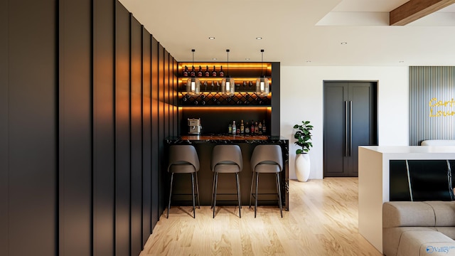 bar featuring hanging light fixtures, paneled refrigerator, and light wood-type flooring