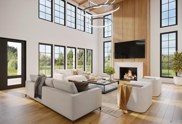 living room with light wood-style floors, wood ceiling, a warm lit fireplace, and a towering ceiling