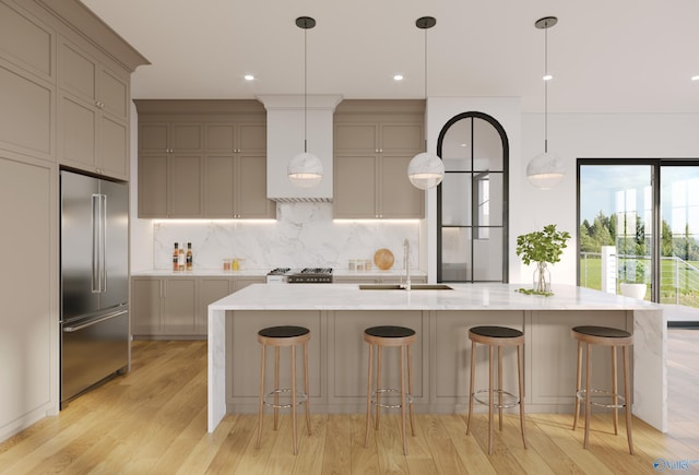 kitchen featuring a sink, a kitchen breakfast bar, a large island with sink, and built in fridge