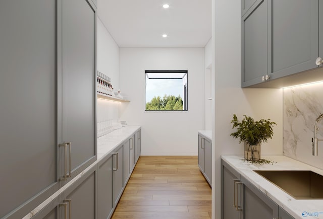 kitchen with light wood-style flooring, recessed lighting, gray cabinets, light stone countertops, and tasteful backsplash