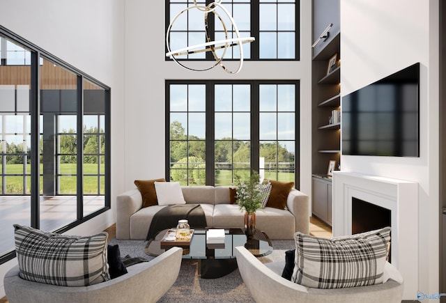 living area featuring a towering ceiling, plenty of natural light, built in shelves, and a chandelier