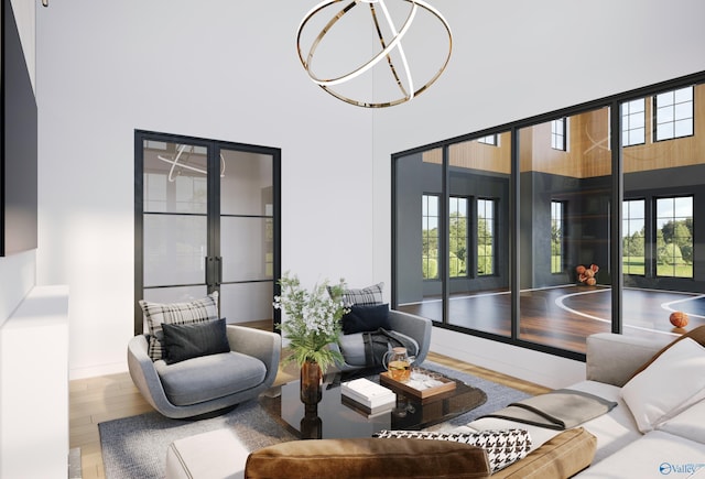 living area with a healthy amount of sunlight, a towering ceiling, an inviting chandelier, and wood finished floors