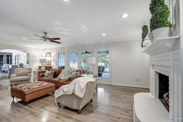 living room with a fireplace, light hardwood / wood-style floors, and ceiling fan